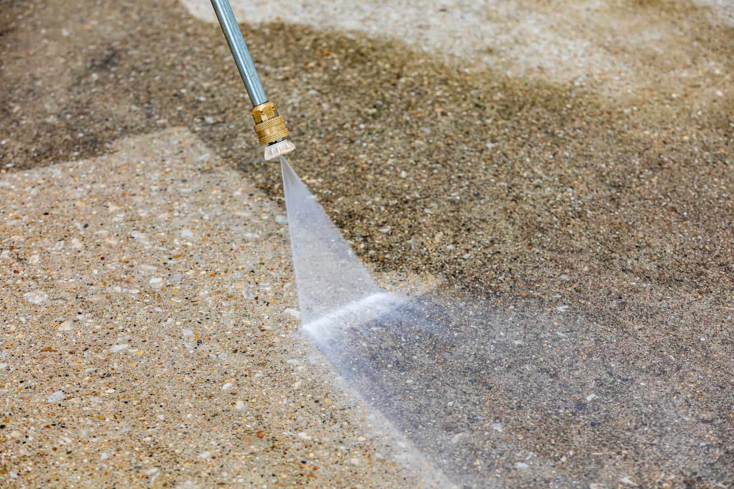 a close-up of a person pressure washing a surface