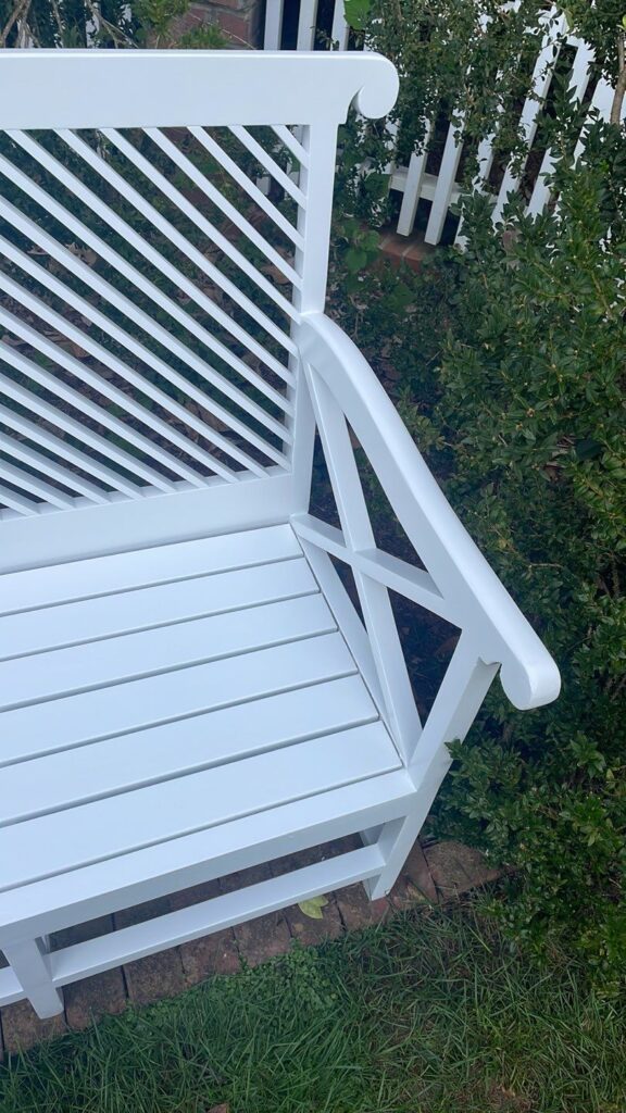 a white bench in a garden- painting company in fort mill sc