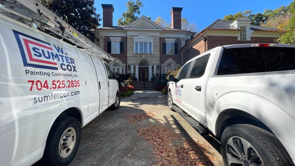 two service cars parked in fron of a two storey house- charlotte nc painting company