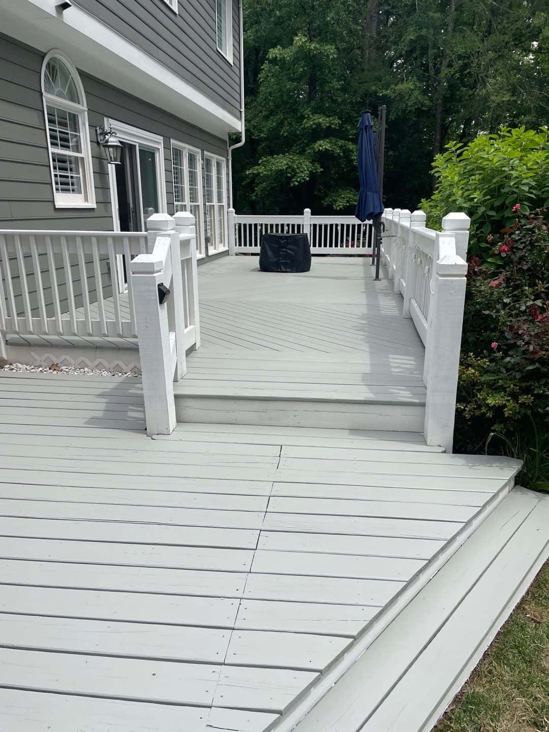 a deck with a white railing and a blue umbrella- exterior house painters in fort mill sc
